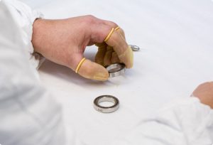 A worker with finger cots picking up a bearing