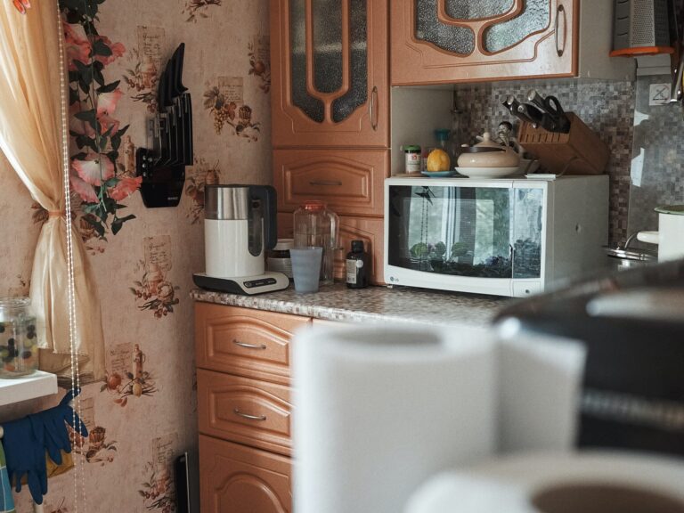 A cluttered kitchen with a large microwave on the counter.